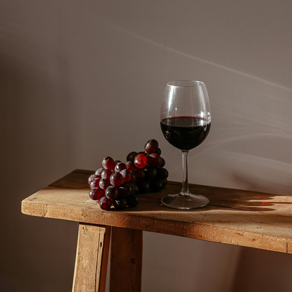 Calice di vino rosso con uva a fianco